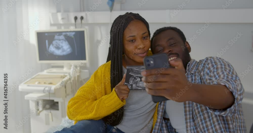Happy smiling married couple taking selfie on smartphone holding ultrasound image Happy smiling married couple taking selfie on smartphone holding ultrasound image