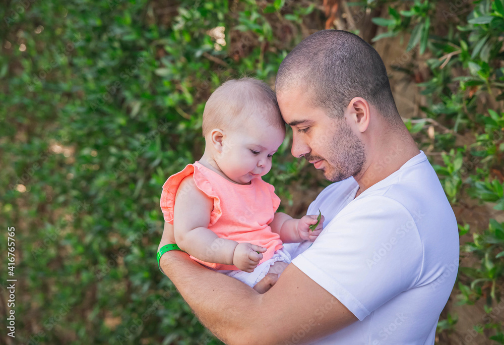 father and daughter leaned their heads to each other on the background of a hedge father and daughter leaned their heads to each other on the background of a hedge