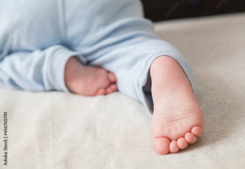 little baby in blue pants crawling on the bed and his small foot close-up little baby in blue pants crawling on the bed and his small foot close-up