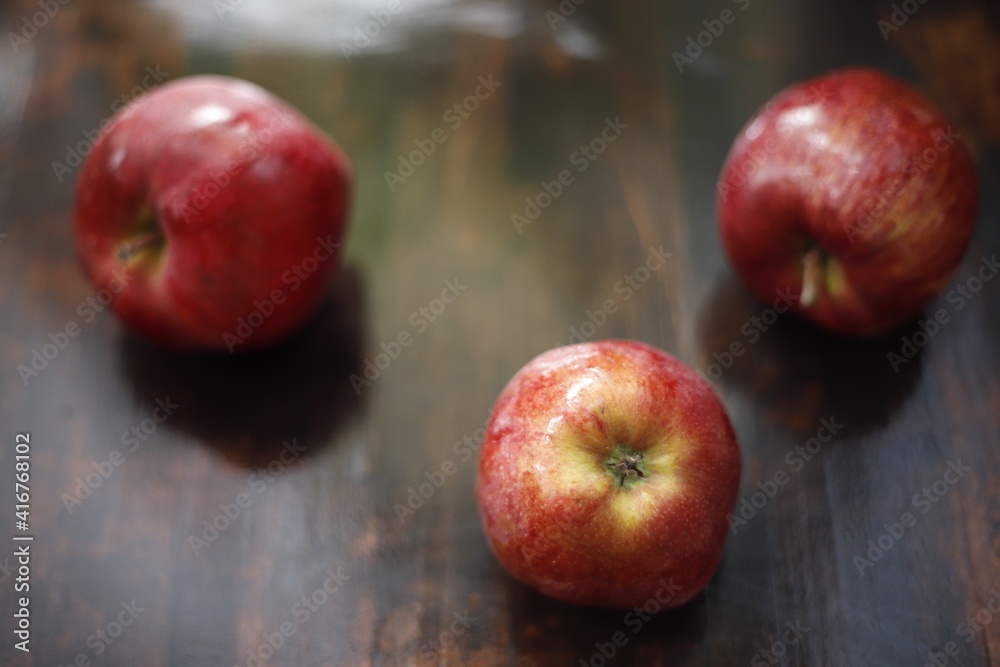 Jabłka czerwono mokre na brązowym stole - obrazy, fototapety, plakaty 