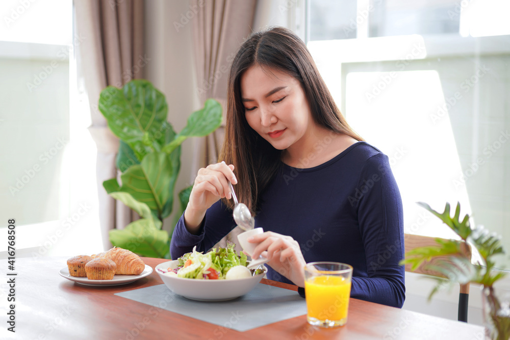 Young asian woman eating healthy salad with fresh vegetable and orange juice on wellness lifestyle