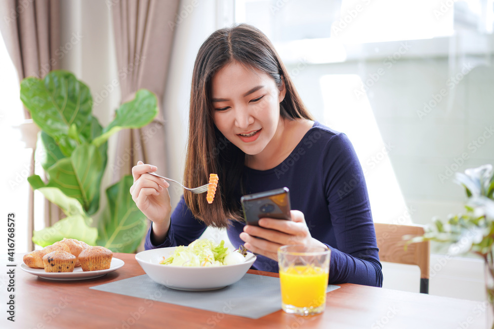 Young asian woman eating healthy salad with fresh vegetable and dip the carrots with a fork