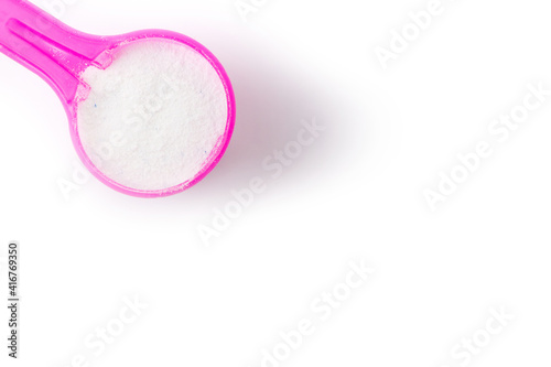 top view of washing powder in pink measuring spoon isolated on white background