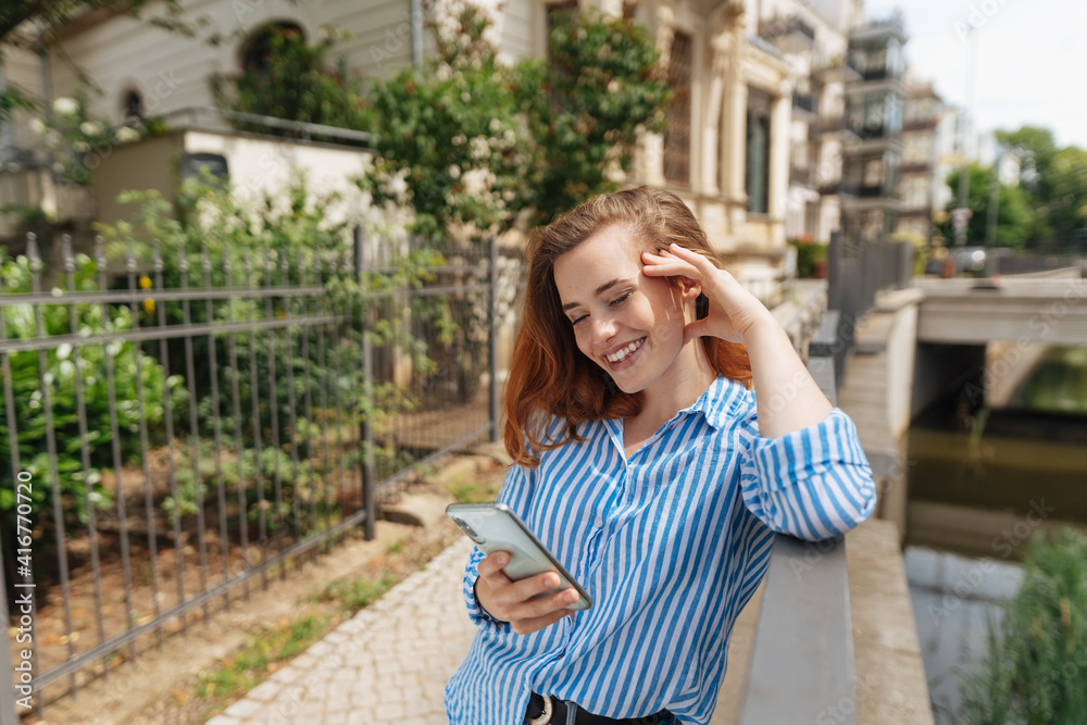 Cute vivacious young woman reading a phone message on a mobile Cute vivacious young woman reading a phone message on a mobile