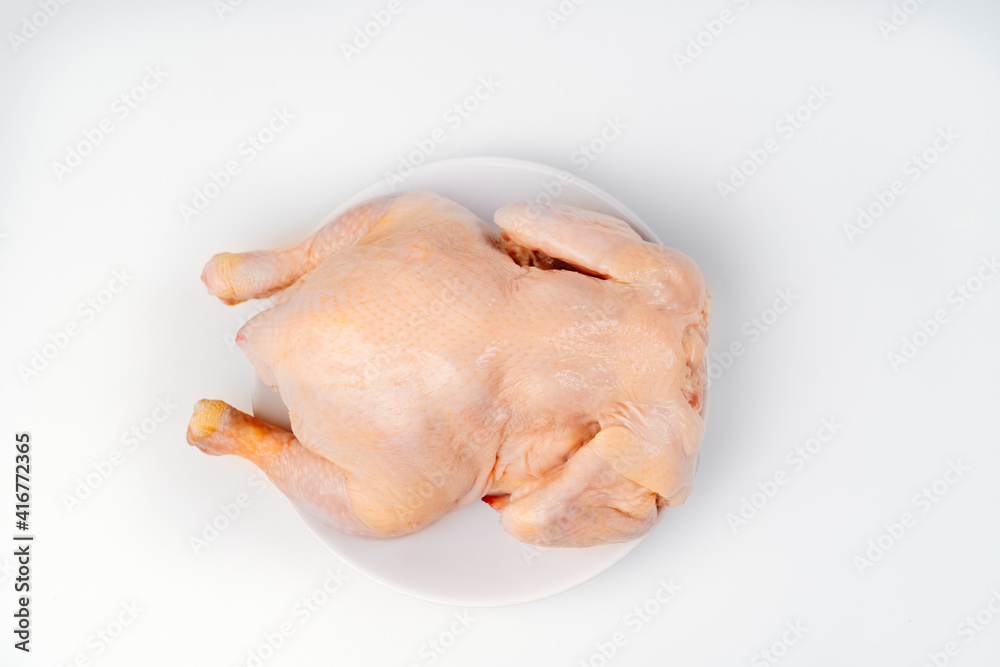 carcass of raw chicken on a white plate on a white background. carcass of raw chicken on a white plate on a white background.