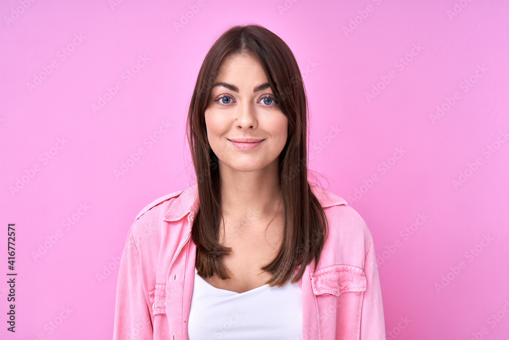 Close Up portrait young brunette woman in pink casual smiling and looking at the camera isolated on studio background with copy space Close Up portrait young brunette woman in pink casual smiling and looking at the camera isolated on studio background with copy space