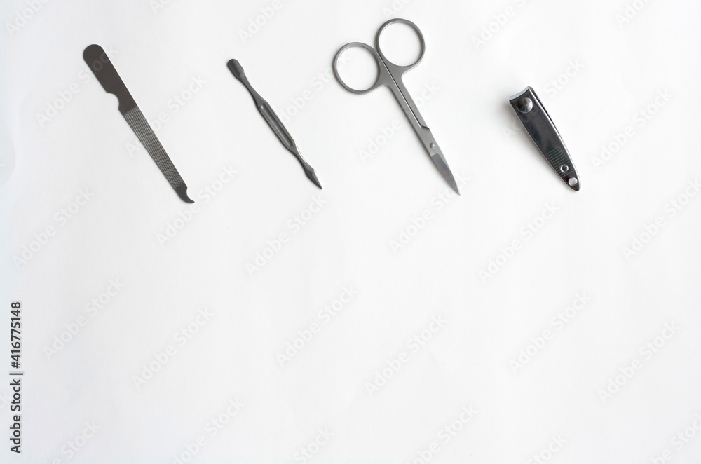 Metal manicure set, tweezers, scissors, file and spatula on white background, flat lay, copy space