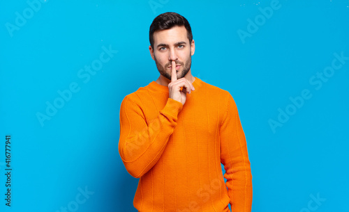 Fotografija handsome adult blond man looking serious and cross with finger pressed to lips d