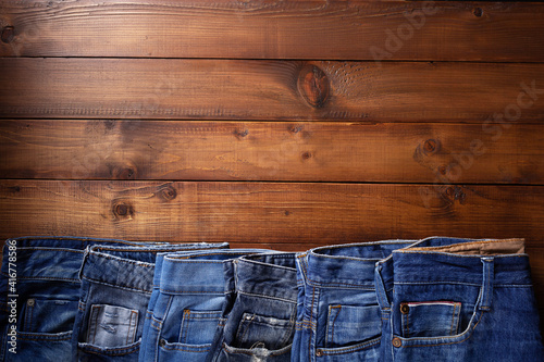 Denim jeans on old wooden background texture table surface. Top view of classic casual jeans