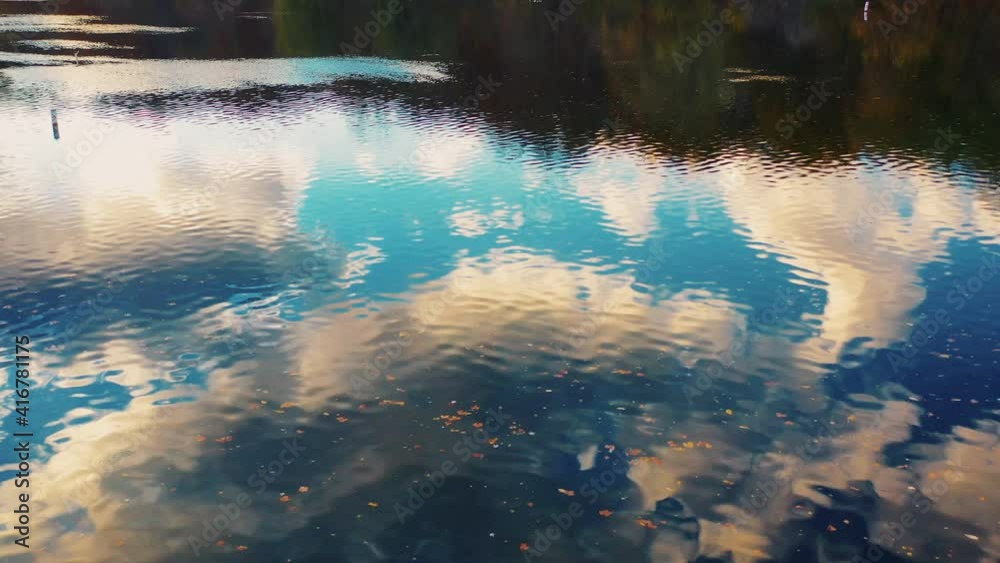 A drone views the beautiful evening golden hour sky through the reflection of the water as it speeds along downstream.