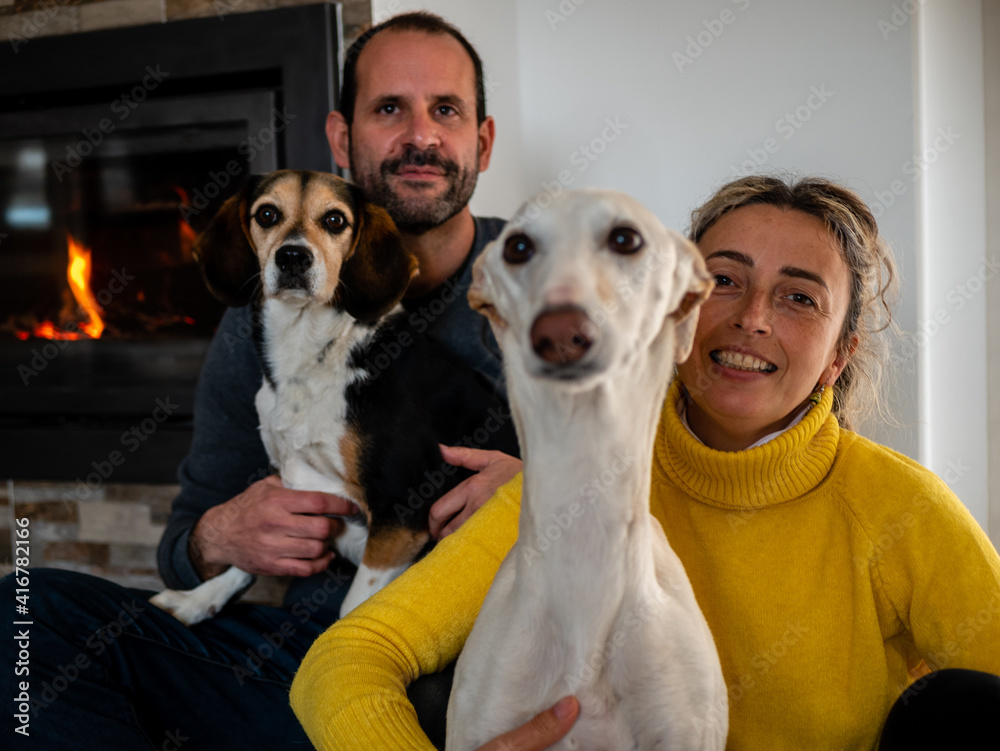 COUPLE WITH THEIR DOGS BY THE FIREPLACE