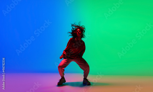 Fototapeta Naklejka Na Ścianę i Meble -  Street. Stylish sportive girl dancing hip-hop in stylish clothes on colorful background at dance hall in neon light. Youth culture, movement, style and fashion, action. Fashionable bright portrait.