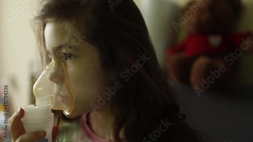 The girl inhales the medicine through the inhaler. Bronchitis treatment. Breathing relief.