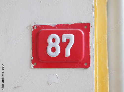 Red house number 87 on the wall photo