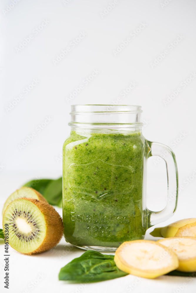 Vegan green smoothie in a jar with spinach, banana and kiwi on a white background Vegan green smoothie in a jar with spinach, banana and kiwi on a white background