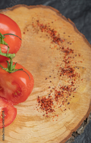 Vertical photo of Fresh ripe tomatoes with red hot chili pepper on wooden board photo