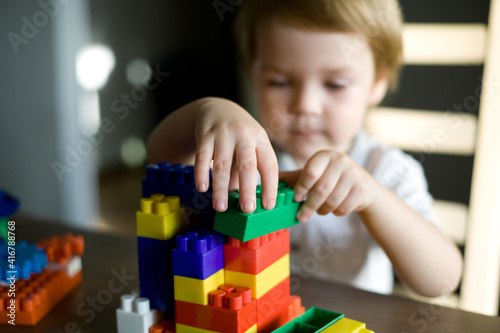 Cute preschooler little boy playing with construction toy blocks building a tower. Child and toys. 