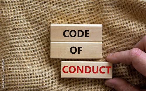 Code of conduct symbol. Concept words 'Code of conduct' on wooden blocks on a beautiful canvas background. Businessman hand. Business and code of conduct concept. Copy space.