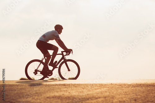 Active cyclist in sport clothing racing on road