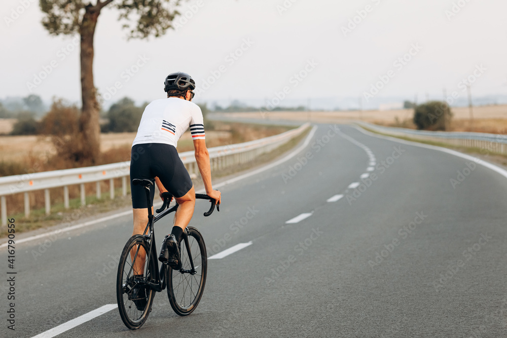 Back view of active man riding bike on fresh air