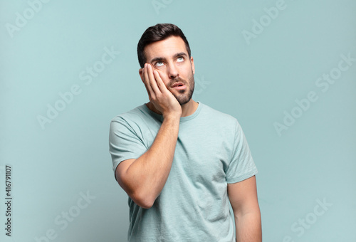 young handsome adult man feeling bored, frustrated and sleepy after a tiresome, dull and tedious task, holding face with hand photo