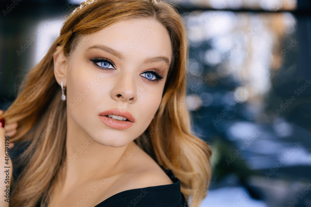 Obraz premium Fashion model with wavy hair. Attractive young girl with curly hair posing in the studio. Face of a beautiful woman with makeup.