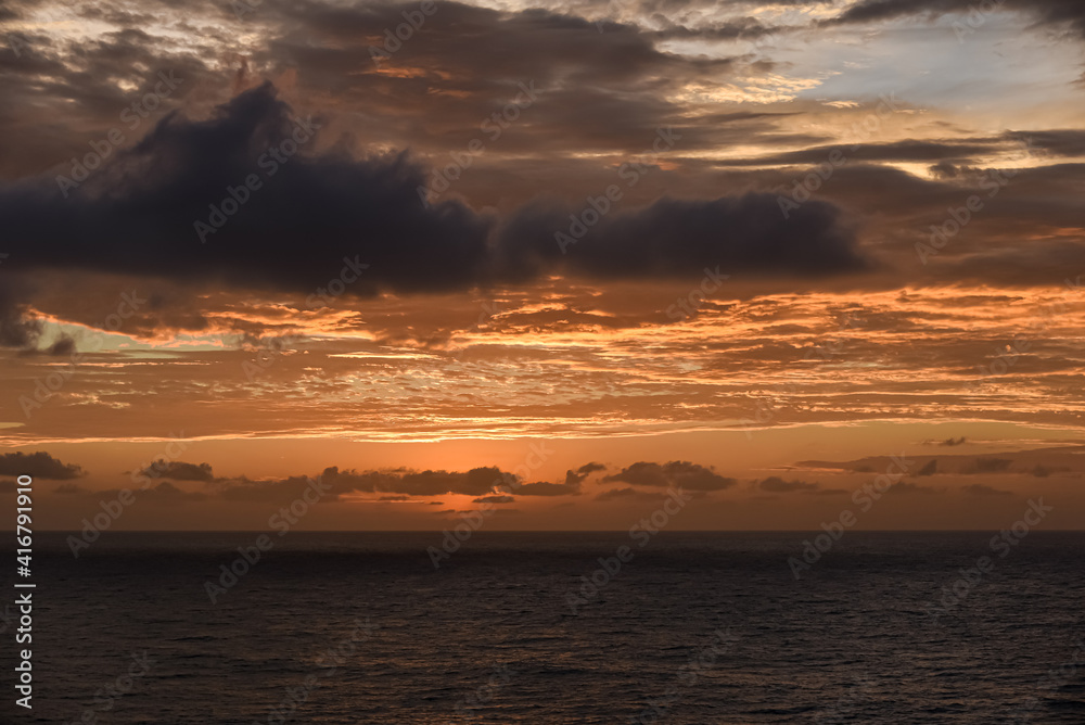 Sunset over the calm sea in a cloudy sky. Abstract and dramatic sunset sky.