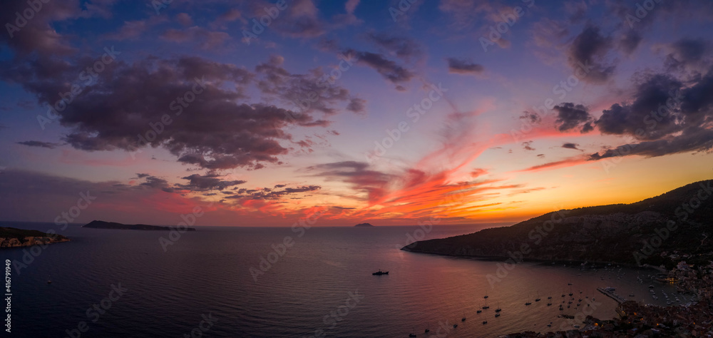 Aerial panorama drone shot of sunset burning sky clouds on Komiza town over Vis Island in Croatia Summer