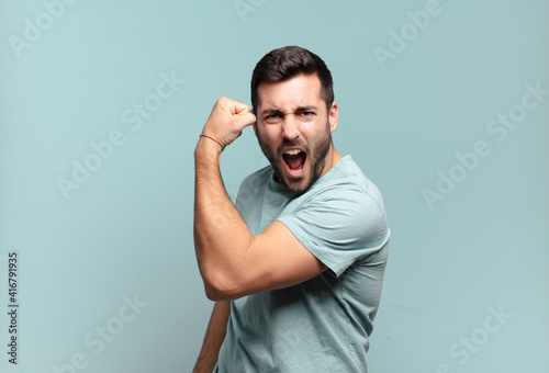 Foto young handsome adult man feeling happy, satisfied and powerful, flexing fit and