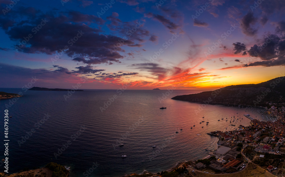 Aerial drone shot of sunset burning sky clouds on Komiza town over Vis Island in Croatia Summer