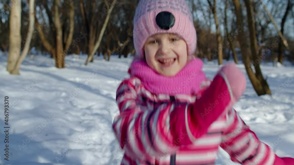 Smiling child kid running on snowy road in winter park forest. Portrait of cute girl having fun, dancing, fooling around outdoors in frosty day sunset. Concept of children at Christmas holidays time Smiling child kid running on snowy road in winter park forest. Portrait of cute girl having fun, dancing, fooling around outdoors in frosty day sunset. Concept of children at Christmas holidays time