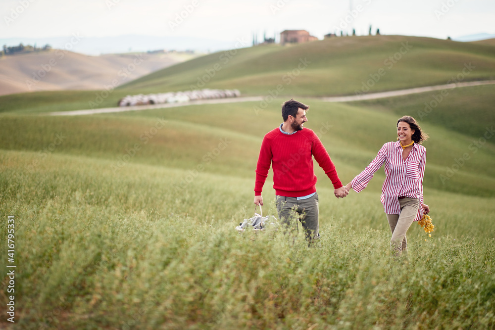 A young cheerful couple feeling happy while walking a large meadow together. Love, relationship, together, nature