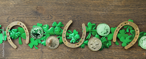 St Patricks Day border of shamrocks, gold coins on rustic wooden background photo