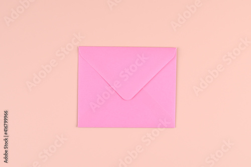 Top view of a bright pink envelope on a pastel pink background. Festive mockup with envelope