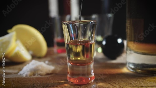 Primer plano chupito de tequila reposado, sal y rodaja de limón fondo negro cámara lenta