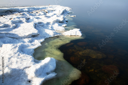 Ice covered rocky coast of the Baltic Sea on wintertime in Latvia. White snow, ice covers the land on seaside. 