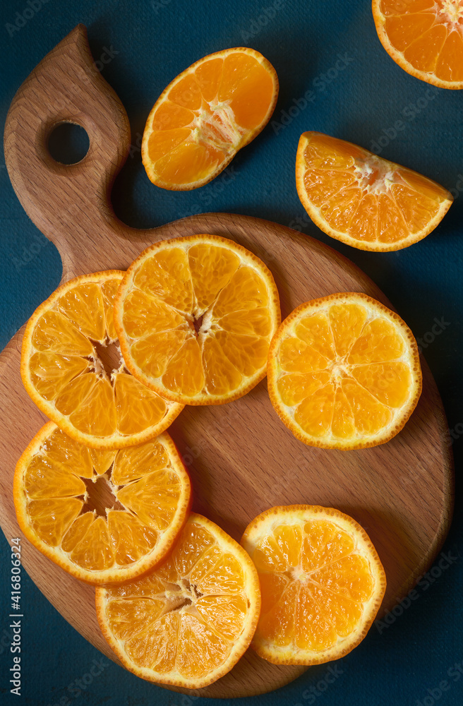 Fototapeta premium Tangerine or mandarin fruit sliced on a wooden board, top view