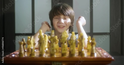 Child boy playing chess and thinking about chess move. photo