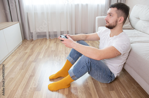 hipster man holding joystick while playing computer games. Computer games concept. Guy sitting on comfort sofa and playing video games.