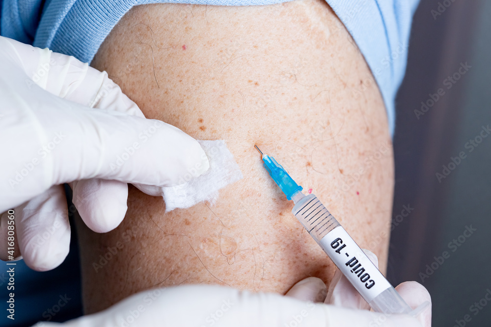 An elderly man of Caucasian appearance in a mask receives a dose of vaccine An elderly man of Caucasian appearance in a mask receives a dose of vaccine