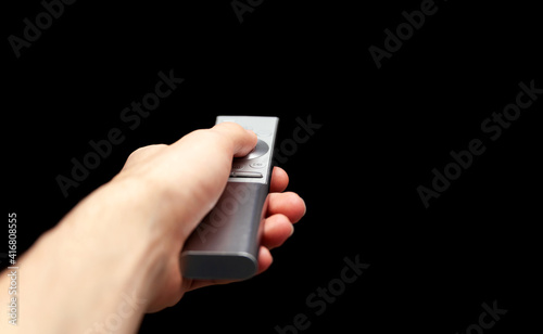 Hand holding a TV remote control, first person pov, man changing channels, isolated, cut out, blank black screen. Pressing a button on a modern television remote, media channel surfing, copy space