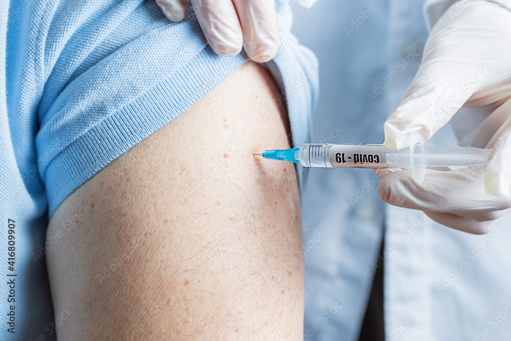 A doctor holds a syringe with a coronavirus vaccine in his hands and injects