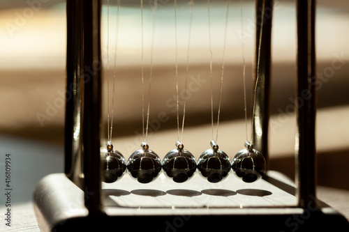 Simple Newtons cradle in sunlight, macro, metal balls in a row, structure extreme closeup. Inertia physical concept, science, fun and education, physics lesson simple toy model, teaching aids, nobody photo