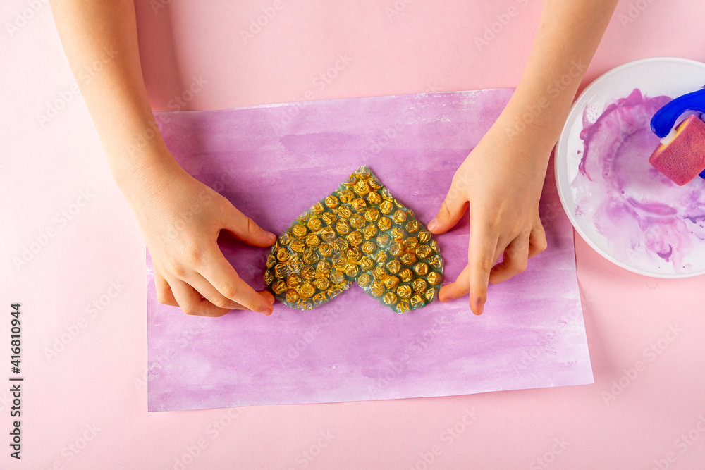 Obraz premium DIY and kids creativity Step by step instruction: Drawing greeting card non-standard method. Step2 apply gold paint to heart-shaped bubble wrap. Valentines, womens and mothers day craft.