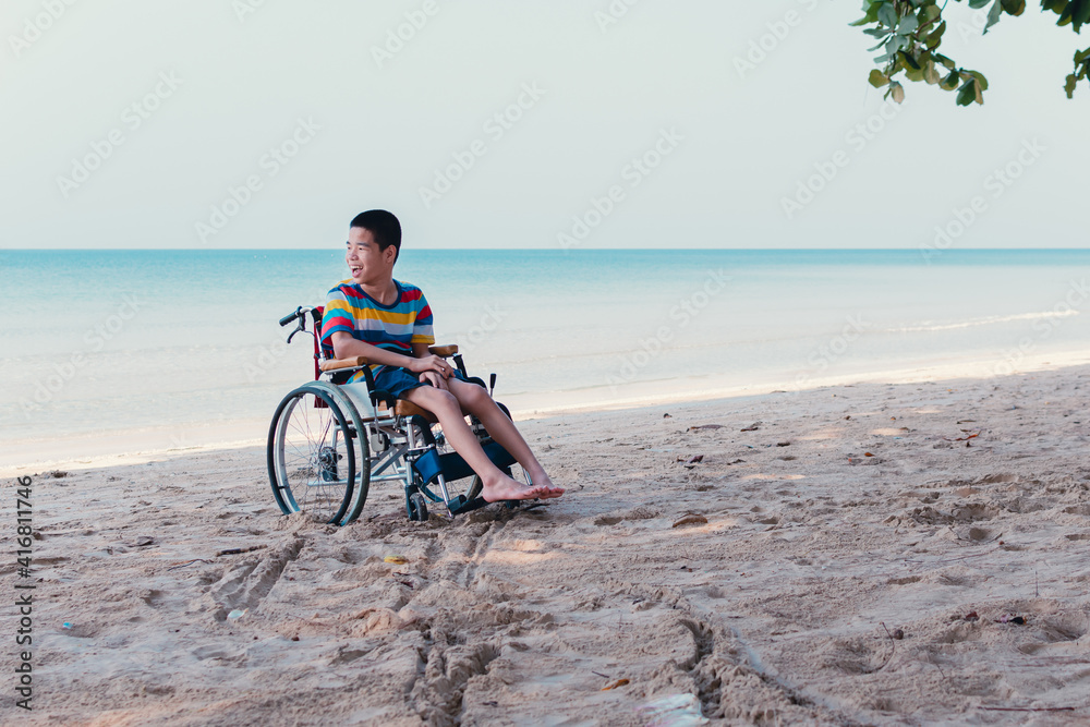 Obraz premium Asian special child on wheelchair is fun, playing ball and exercise activity on sea beach at summer, Lifestyle of disability child, Life in the education age, Happy disabled kid in travel concept.