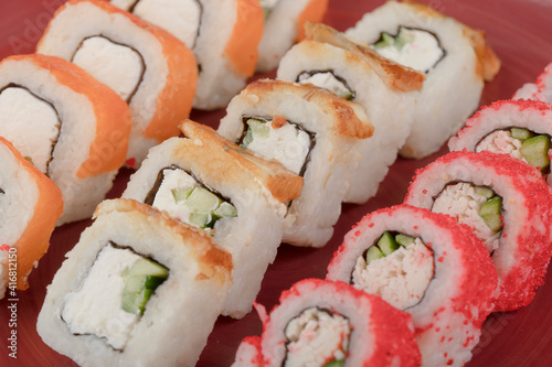 Red plate of various delicious sushi rolls background
