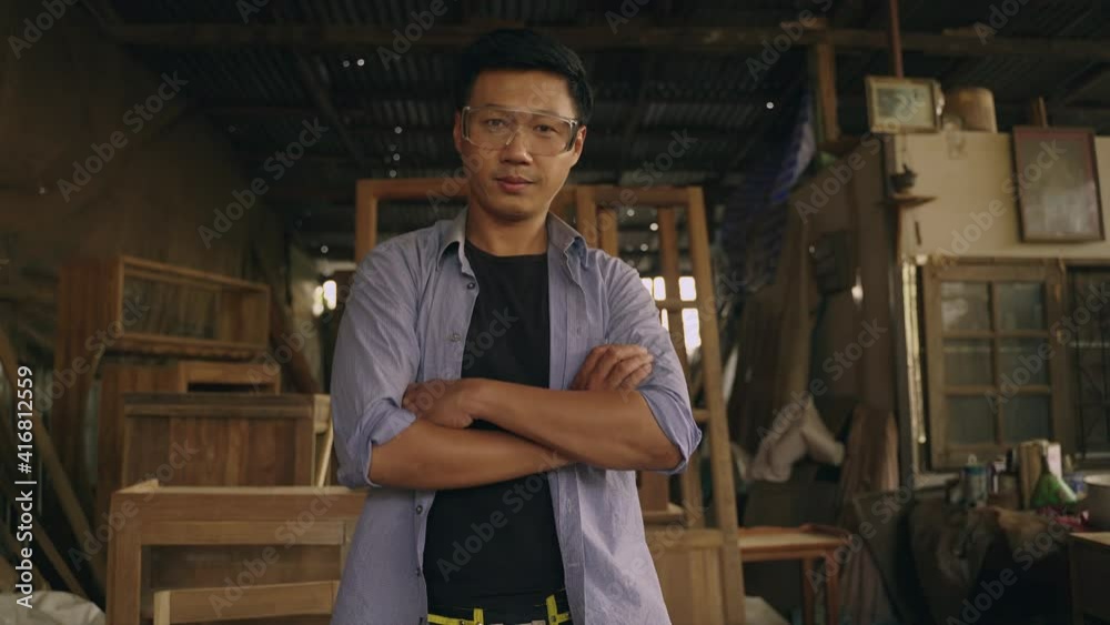 Portrait of asian craftsman with equipment standing in workshop and looking at camera. Carpenter in workplace. Thai man carpenter.