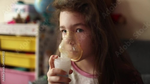 The girl inhales the medicine through the inhaler. Bronchitis treatment. Breathing relief.