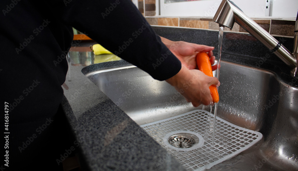Man washing vegetables in the kitchen sink