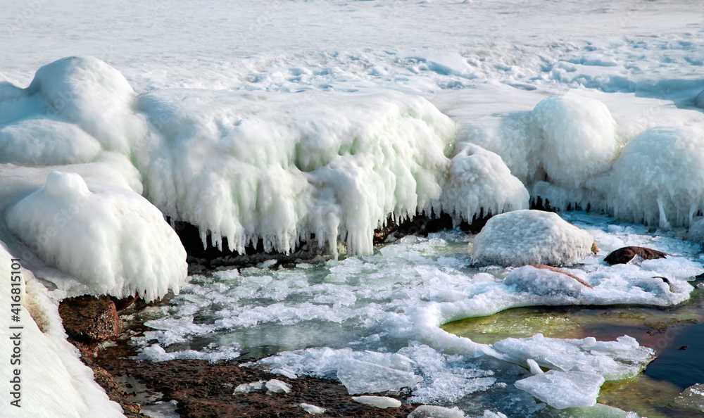Ice covered rocky coast of the Baltic Sea on wintertime in Latvia. White snow, ice covers the land on seaside. Ice covered rocky coast of the Baltic Sea on wintertime in Latvia. White snow, ice covers the land on seaside.
